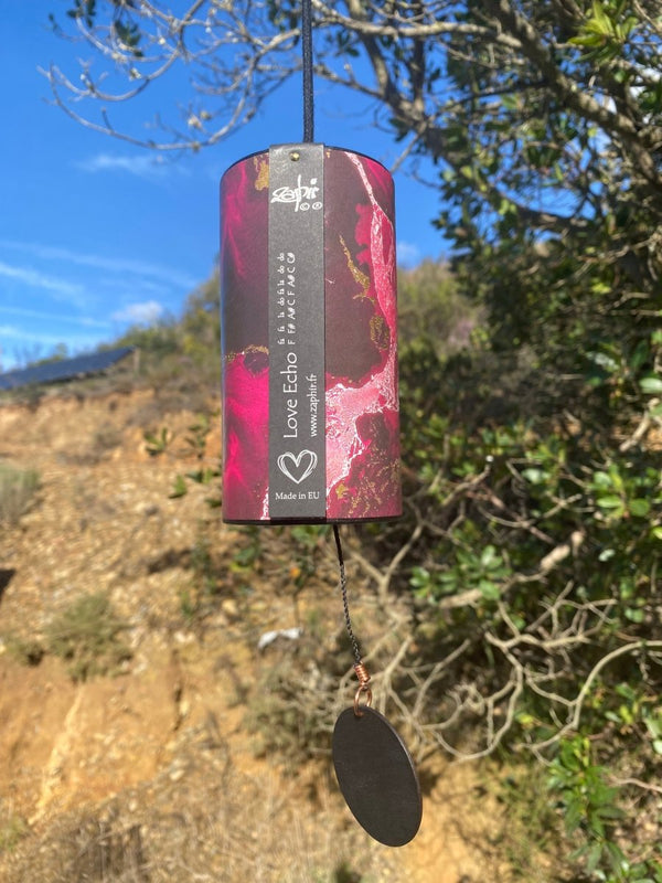Zaphir Chime Love Echo in Shanti Design hanging in a tree, fuchsia color, Chime handmade in France, handcrafted cellulose resonance tube with eight silver-welded metal cords,